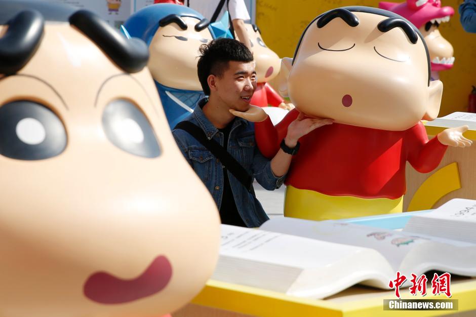 4月22日，游客與蠟筆小新合影?！跋灩P小新25周年紀(jì)念特展”日前在北京開(kāi)展，吸引了不少市民游客。