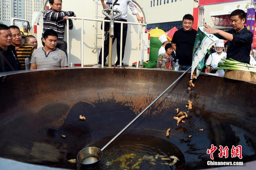 工作人員向大鍋內(nèi)加入油和姜等烹飪調(diào)料。 圖片來源：CFP視覺中國