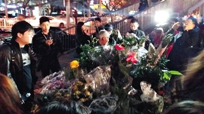 昨晚7時許，三里屯太古里西邊附近一過街天橋旁邊，聞訊而至的網(wǎng)友圍住了賣花老人，爭相買花。 網(wǎng)友“行者橙子”供圖