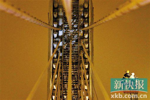 截至今日零時(shí)，男子仍未有下橋舉動(dòng)。圖為公安和消防人員乘消防云梯在高空上和男子交談。